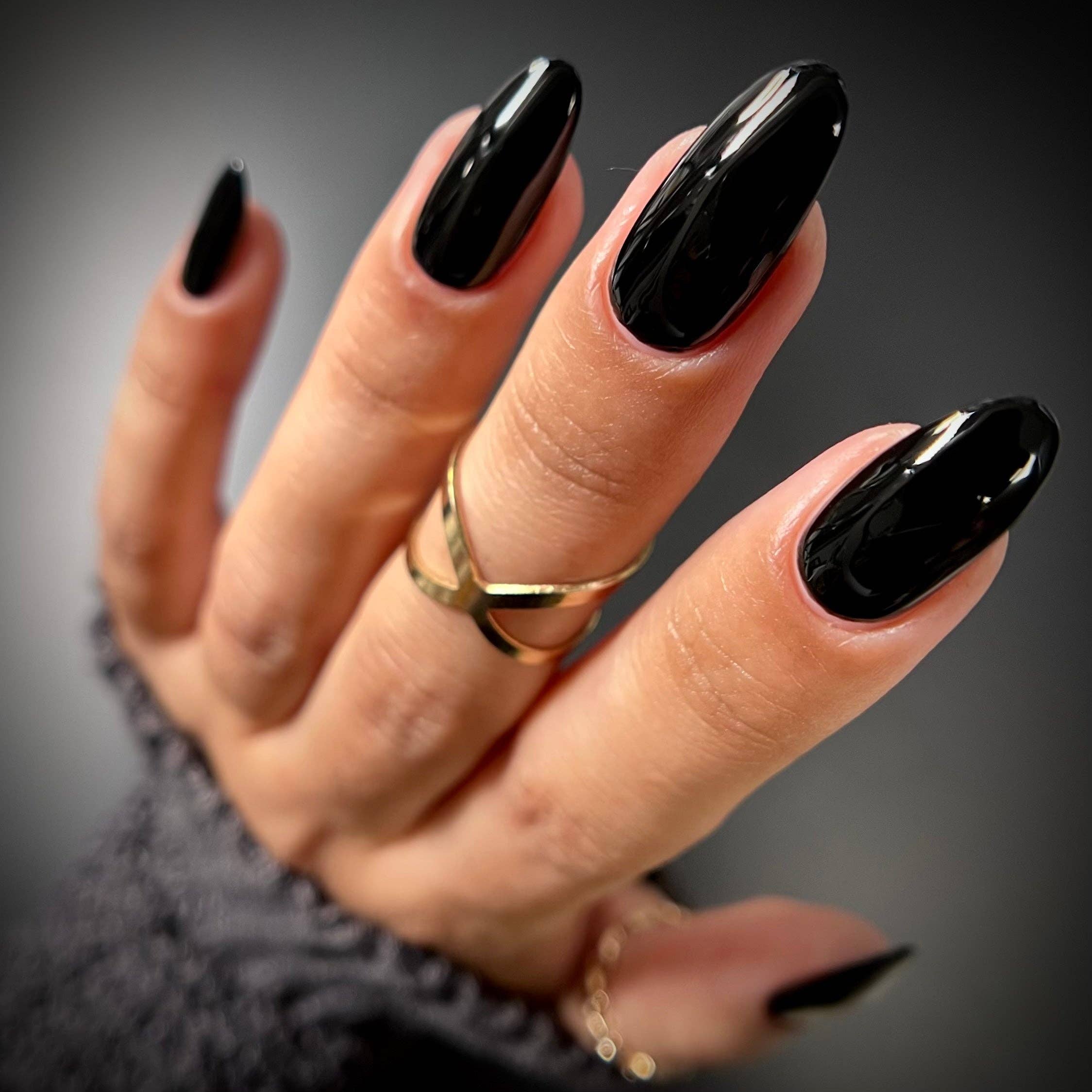 Hand with black nail polish on a dark background