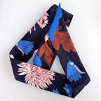 Navy blue scarf with colorful floral and leaf patterns on a white background