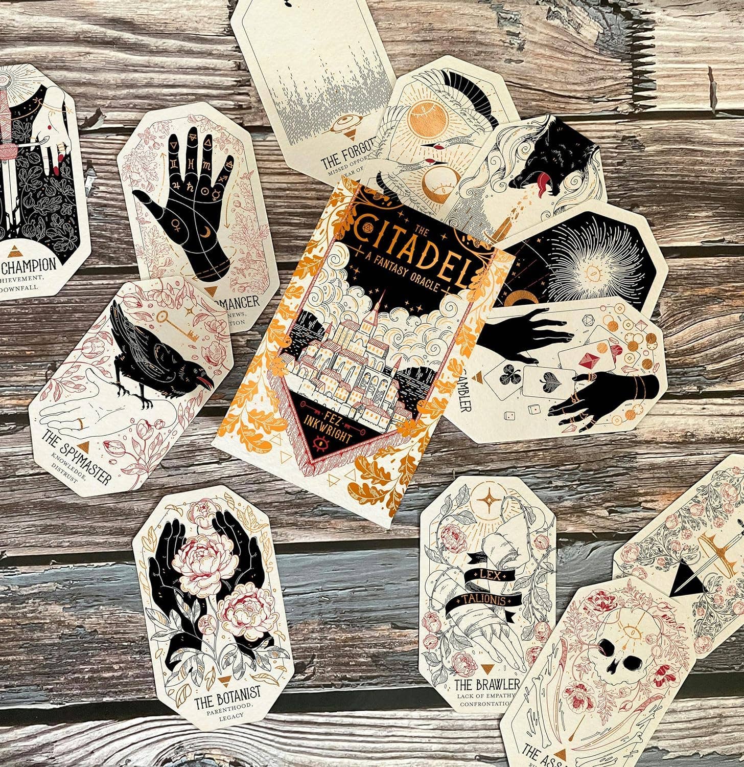 Collection of tarot cards on a wooden surface with 'The Citadel' book.