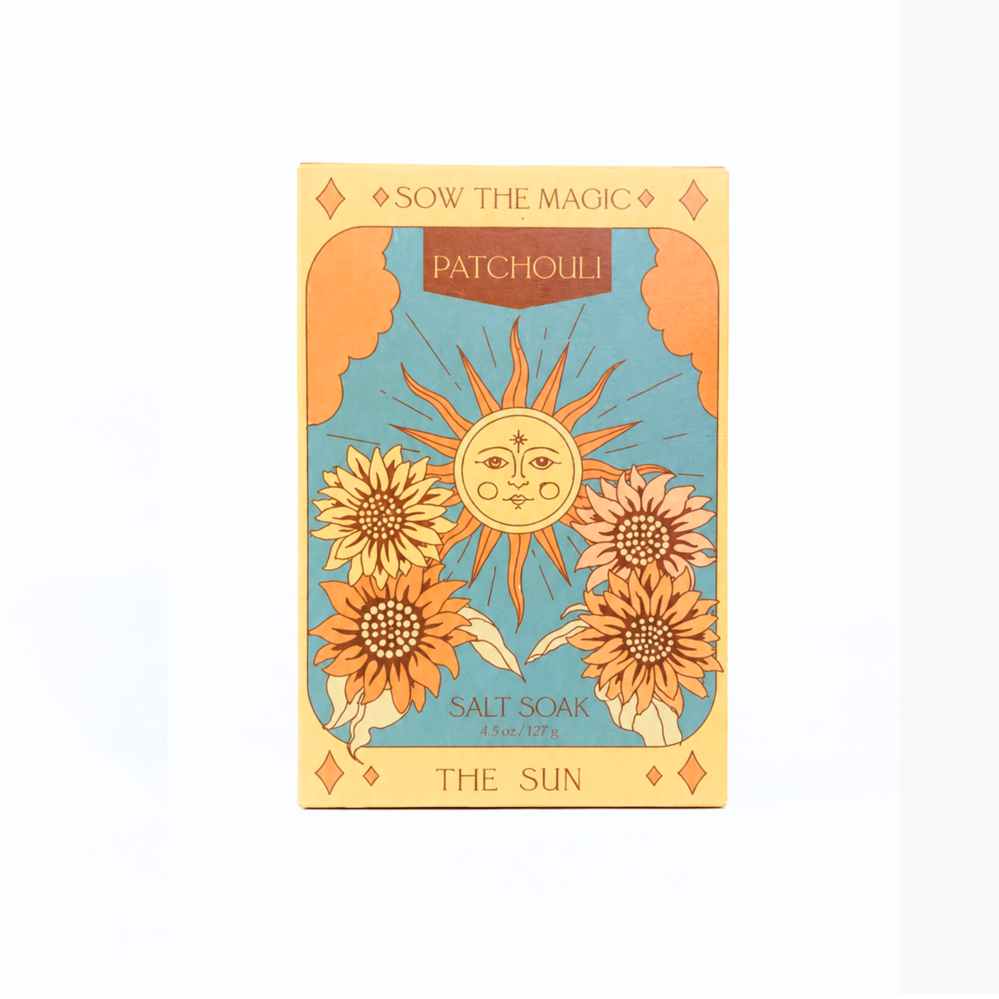 A tarot card style patchouli salt soak packet labeled 'THE SUN' with a central sun face, four sunflowers, and the words 'SOW THE MAGIC' and 'PATCHOULI' on a cream background.
