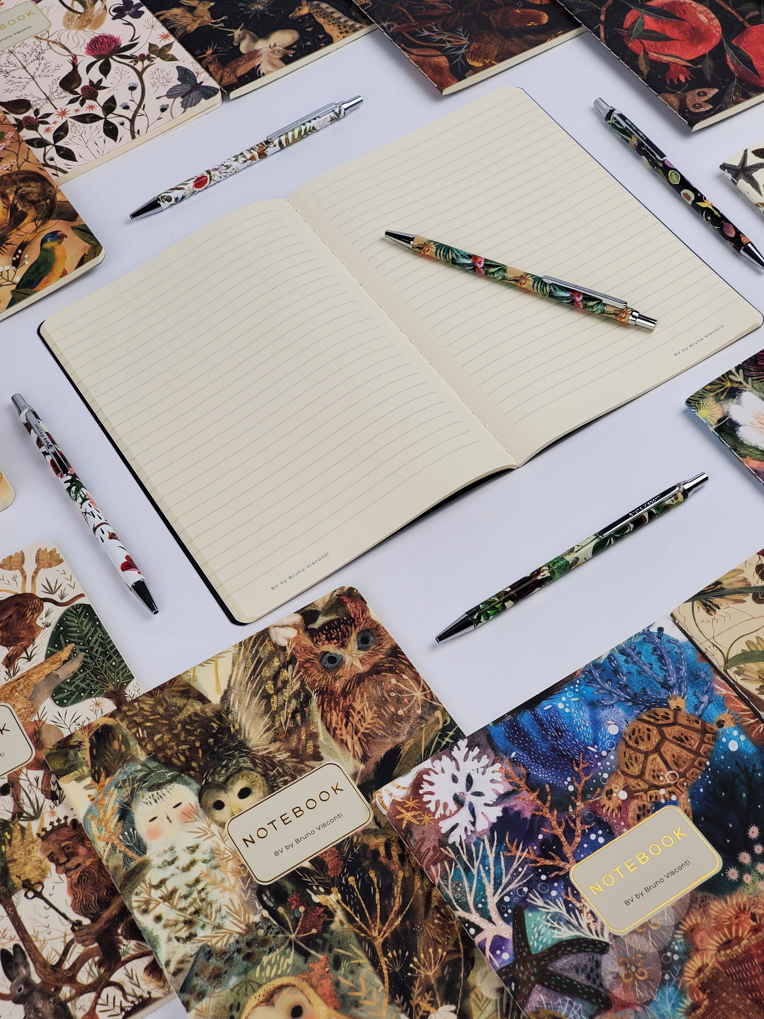 Open notebook with decorative pens and notebooks on a white surface