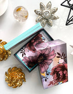 Floral design box with decorative brooches on a white surface