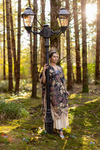 Woman in a floral dress standing next to a vintage lamp post in a forest