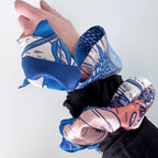 Hand wearing a blue and white patterned glove on a plain background