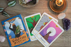 Four tarot cards on a wooden surface with a candle and crystals.