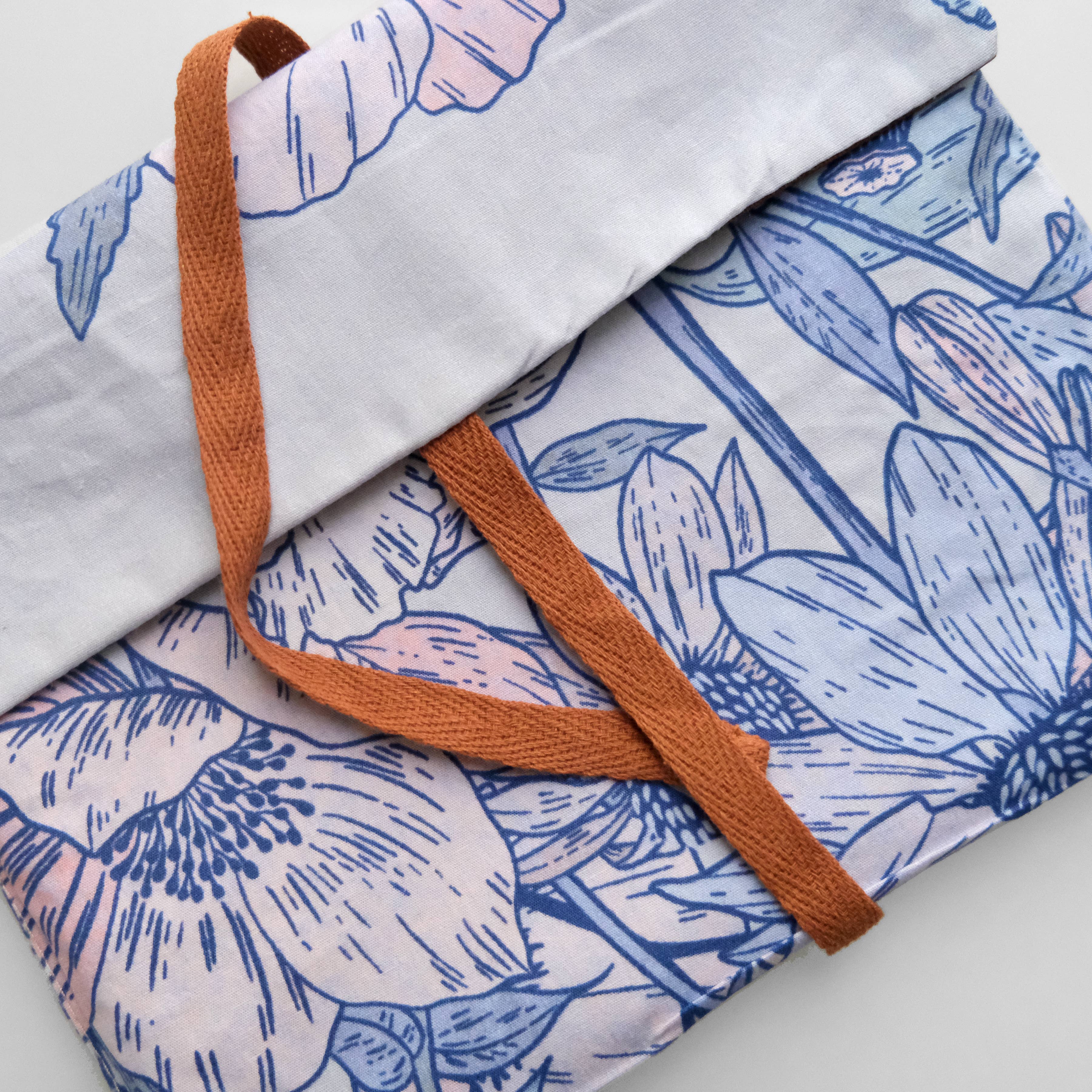 Floral-patterned fabric with a brown strap on a light background