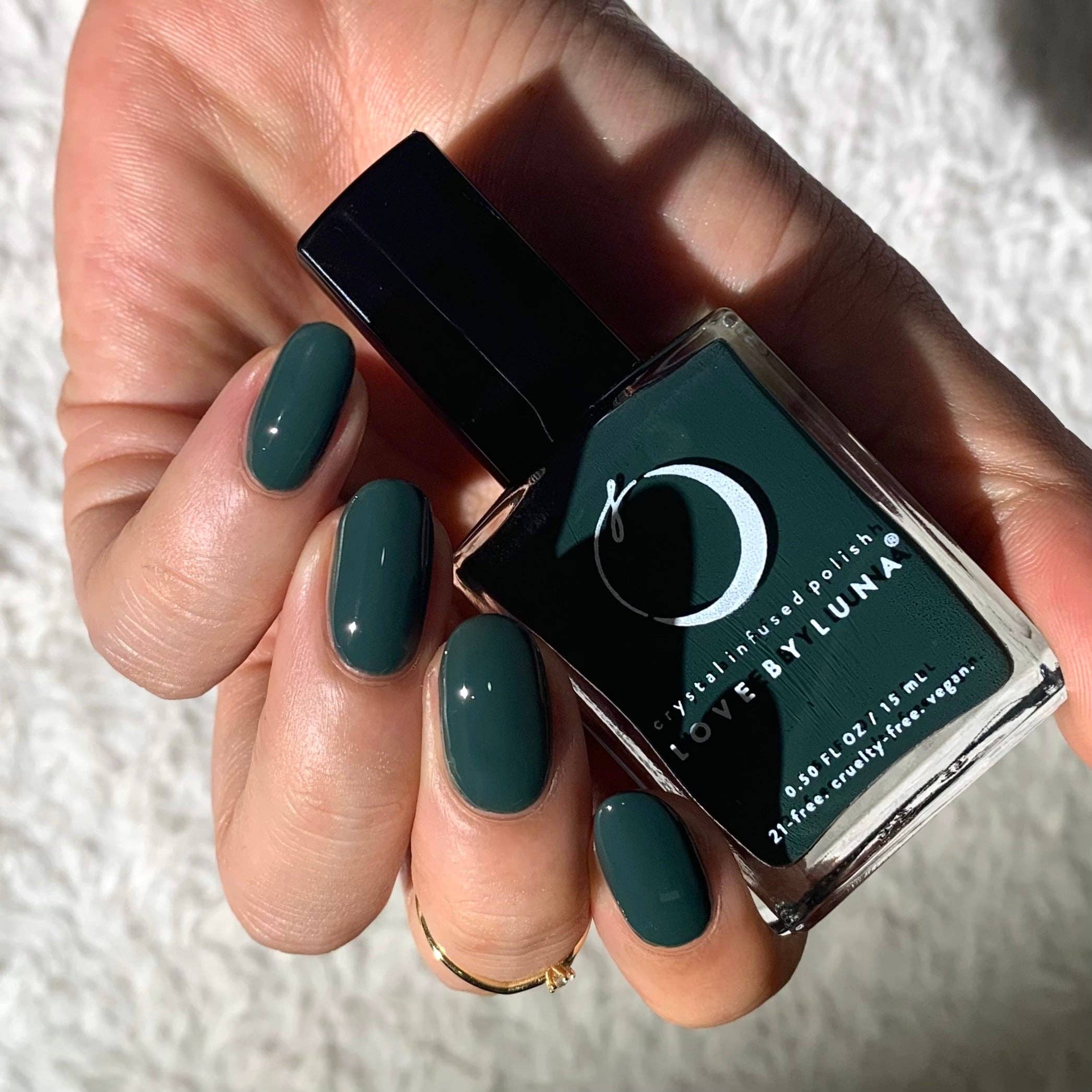 Hand holding a bottle of green nail polish with 'Luna' branding.