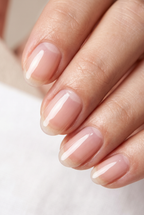 Close-up of a hand with light pink nail polish on a neutral background