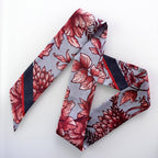A patterned necktie with a gray base, red and pink floral motifs, and dark navy diagonal stripes, arranged on a plain white background.