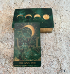 Green tarot card with celestial design on a textured surface