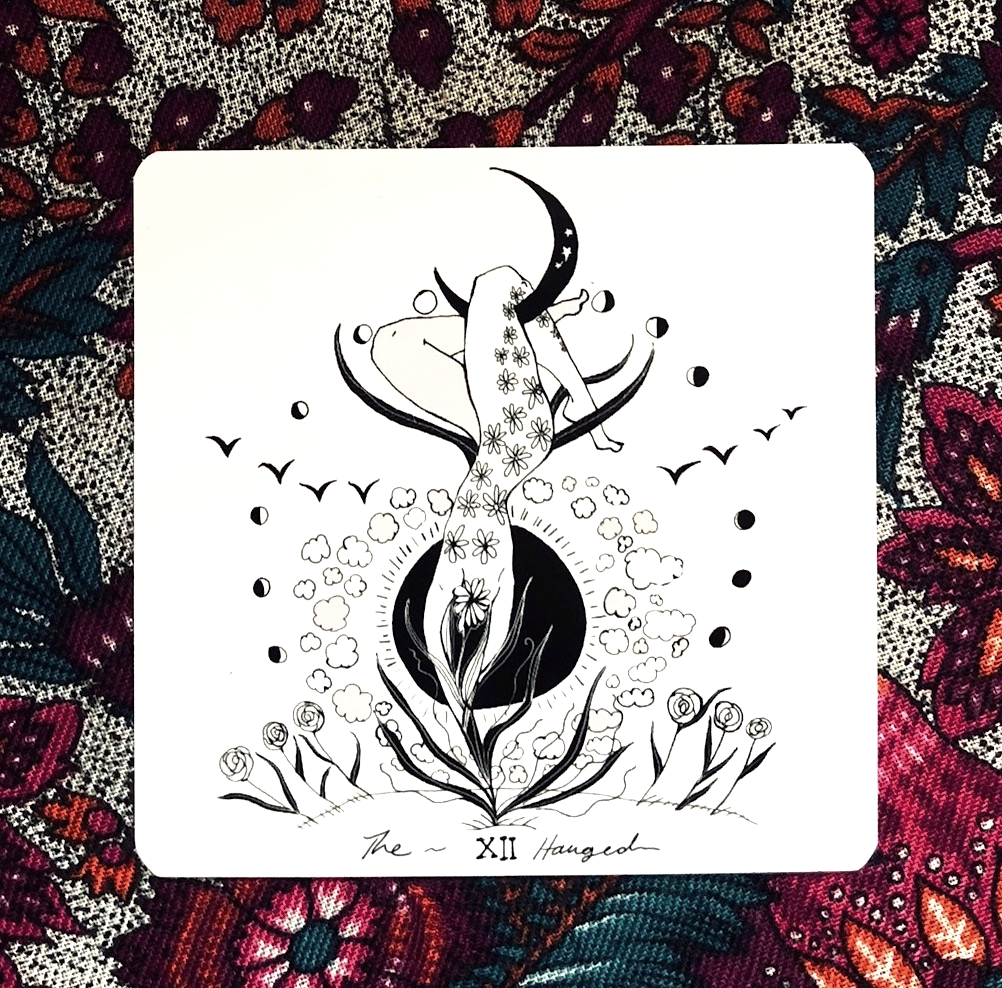 Tarot card with a black and white illustration of a woman and moon on a colorful floral background