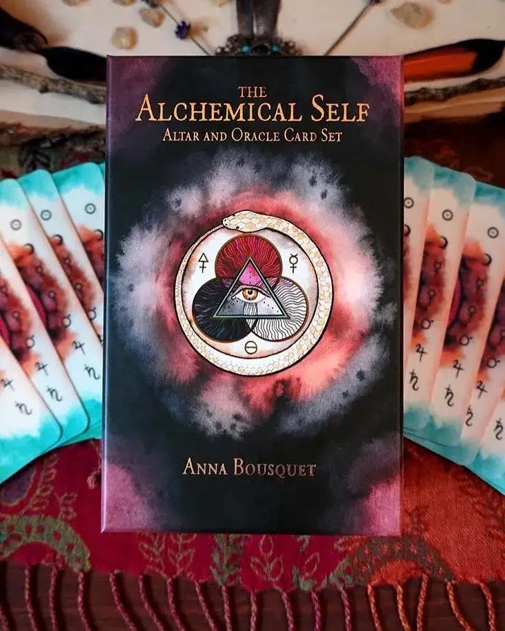 The Alchemical Self Altar and Oracle Card Set box by Anna Bousquet, displayed upright with cards fanned out on both sides on a red patterned textile.