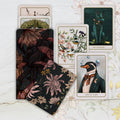Collection of tarot cards with artistic designs on a floral-patterned surface