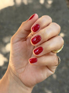 Hand with red nail polish against a blurred background