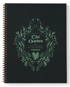 A spiral-bound yearly planner titled 'The Garden' from 'A Vital Plant Parade', featuring a botanical wreath design in mint green on a matte black cover.