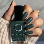 Hand holding a bottle of green nail polish with 'Love by Luna' branding.