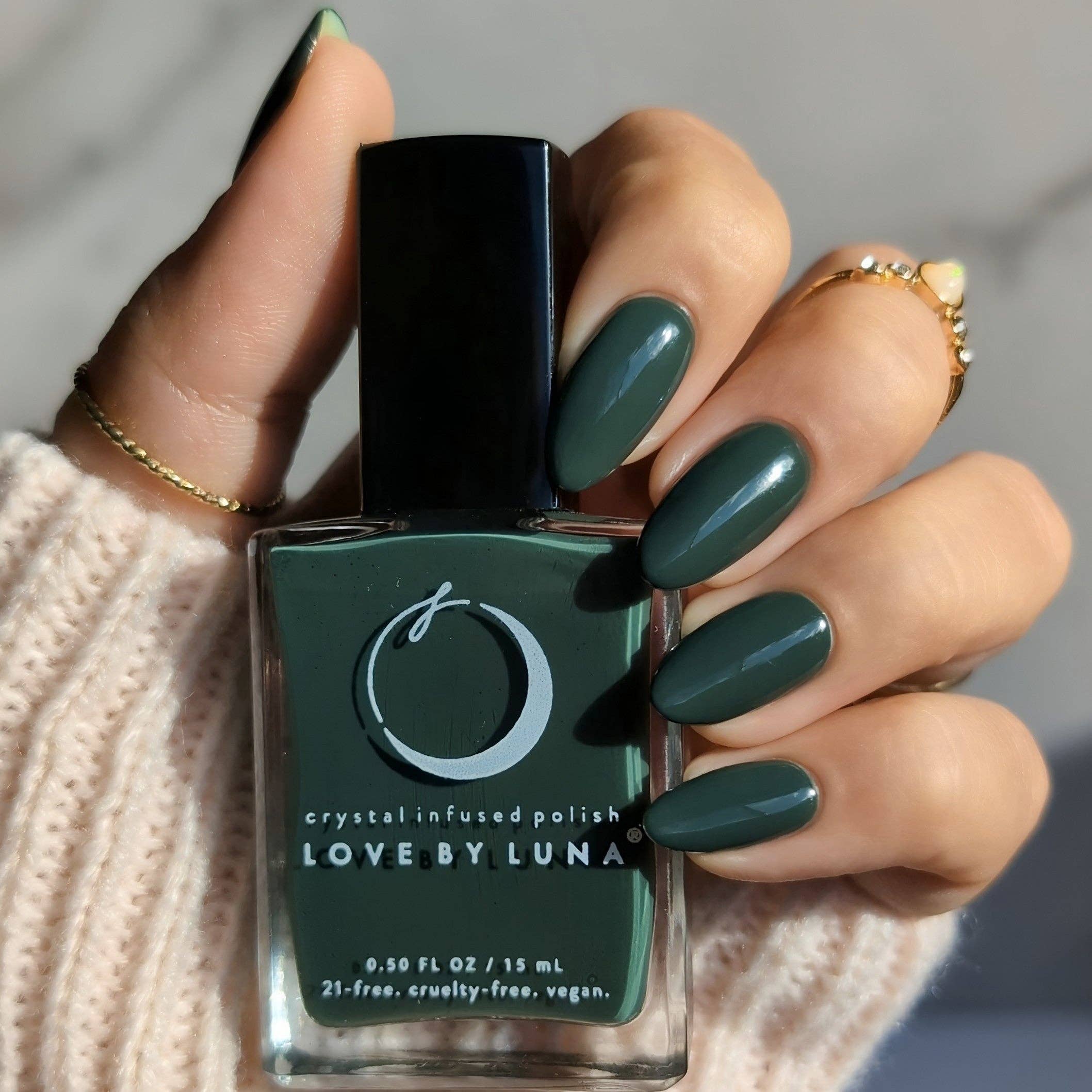 Hand holding a bottle of green nail polish with 'Love by Luna' branding.