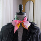 Mannequin wearing a colorful scarf with a black jacket against a neutral background