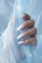 Hand with light-colored nails holding sheer fabric