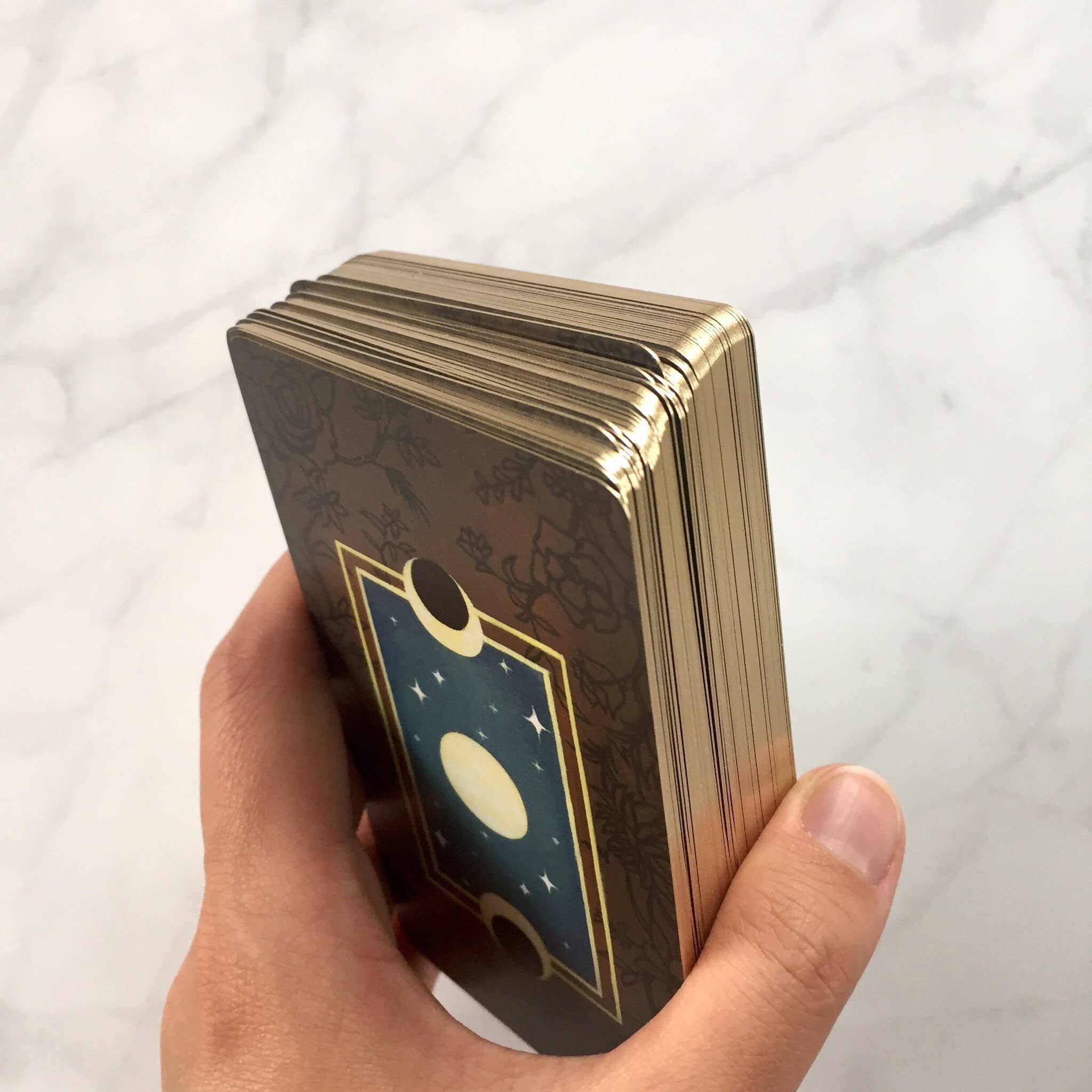 Hand holding a deck of tarot cards with a white background