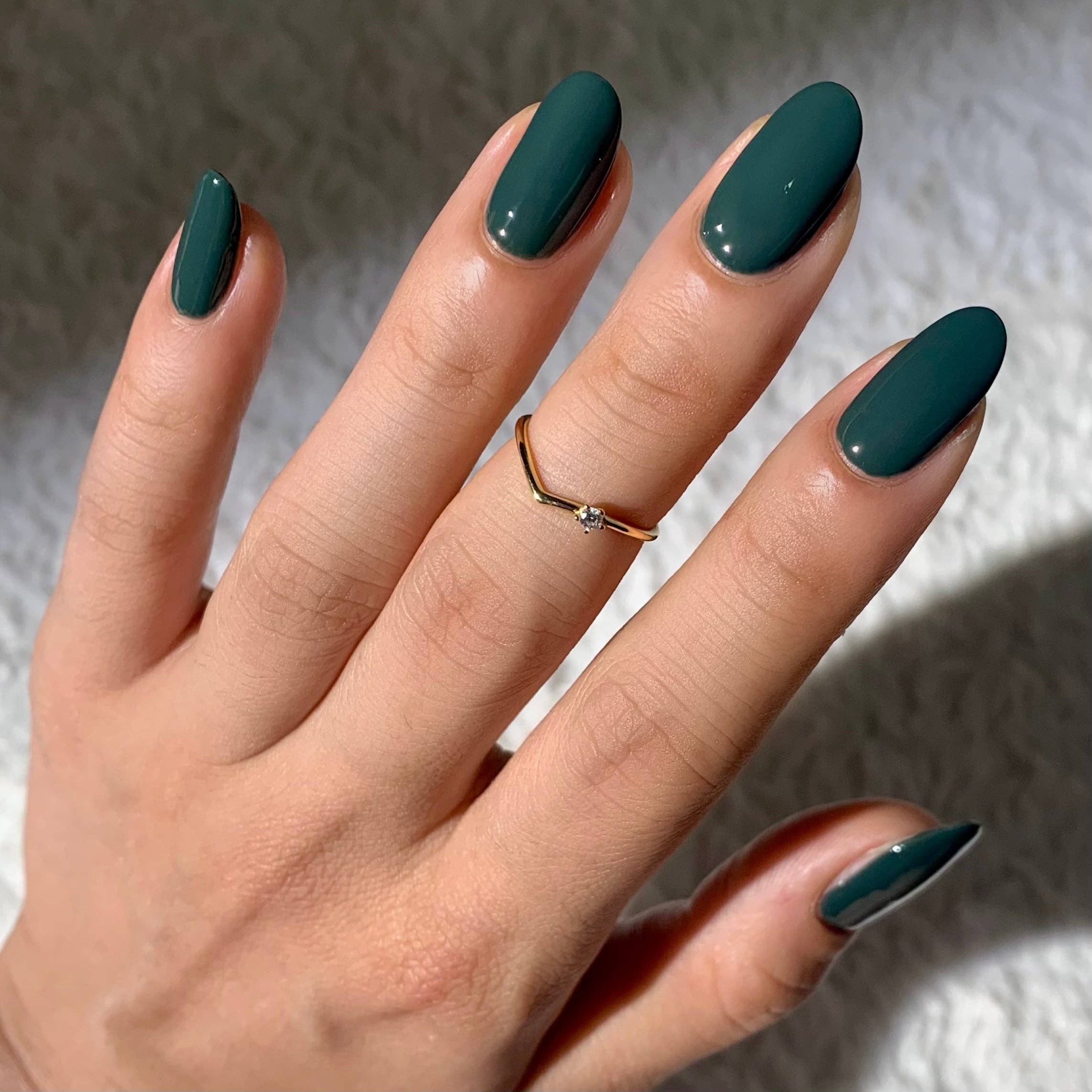 Hand with teal nail polish on a neutral background