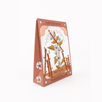 A triangular salt soap packaging box for 'Sow the Magic' brand's 'Marshmallow' Salt Soap, featuring a white center with brown marshmallow stems and flowers, and a terracotta-colored border.