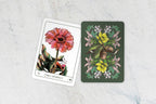 Two tarot cards with floral designs on a light gray surface