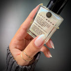 Hand holding a small bottle labeled 'Full Moon' against a dark background