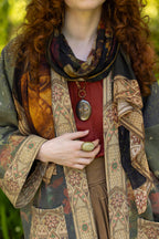 Person wearing a patterned scarf and coat with a forest background