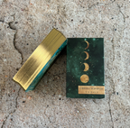 Gold and green rectangular box with celestial design on a concrete surface