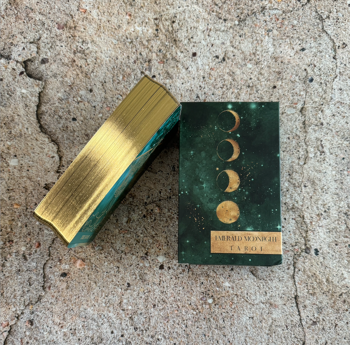 Gold and green rectangular box with celestial design on a concrete surface