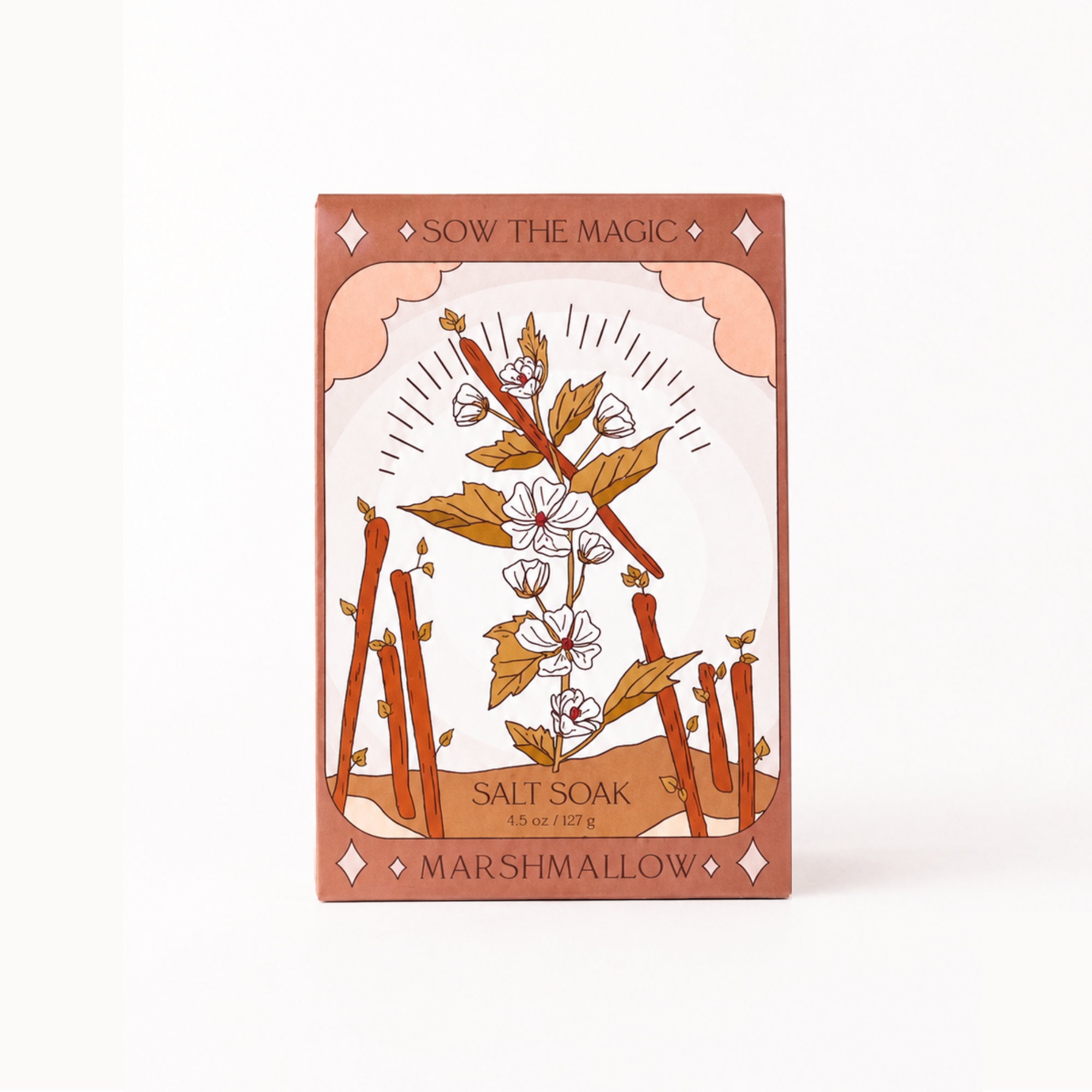 A rectangular box of Marshmallow Salt Soak featuring an Art Deco style illustration of a plant with white blossoms, brown leaves, and orange-brown branches on a cream background, with a dusty rose border. The text 'SOW THE MAGIC' is at the top and 'MARSHMALLOW SALT SOAK' is at the bottom.