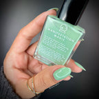 Hand holding a bottle of green nail polish with 'Manifestation Magic' text.