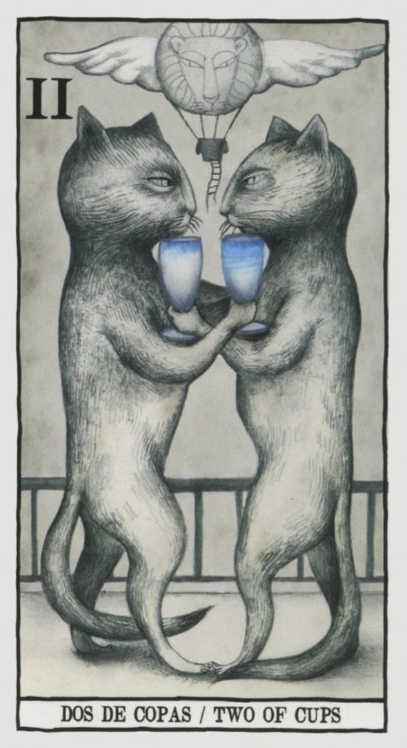 A tarot-style illustration labeled 'DOS DE COPAS / TWO OF CUPS' showing two anthropomorphic cats standing on hind legs and drinking from blue cups, with a winged hot air balloon and sun motif above.