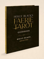 Holly Black's Faerie Tarot Guidebook, featuring a textured black cover with elegant gold lettering, shown at a three-quarter angle on a light beige background.