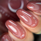 Close-up of a hand with pink nail polish on a blurred background