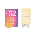 Card deck packaging with a card displayed on a stand, titled '52 Cards to Manifest'.