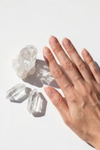 Hand next to three clear crystals on a light background