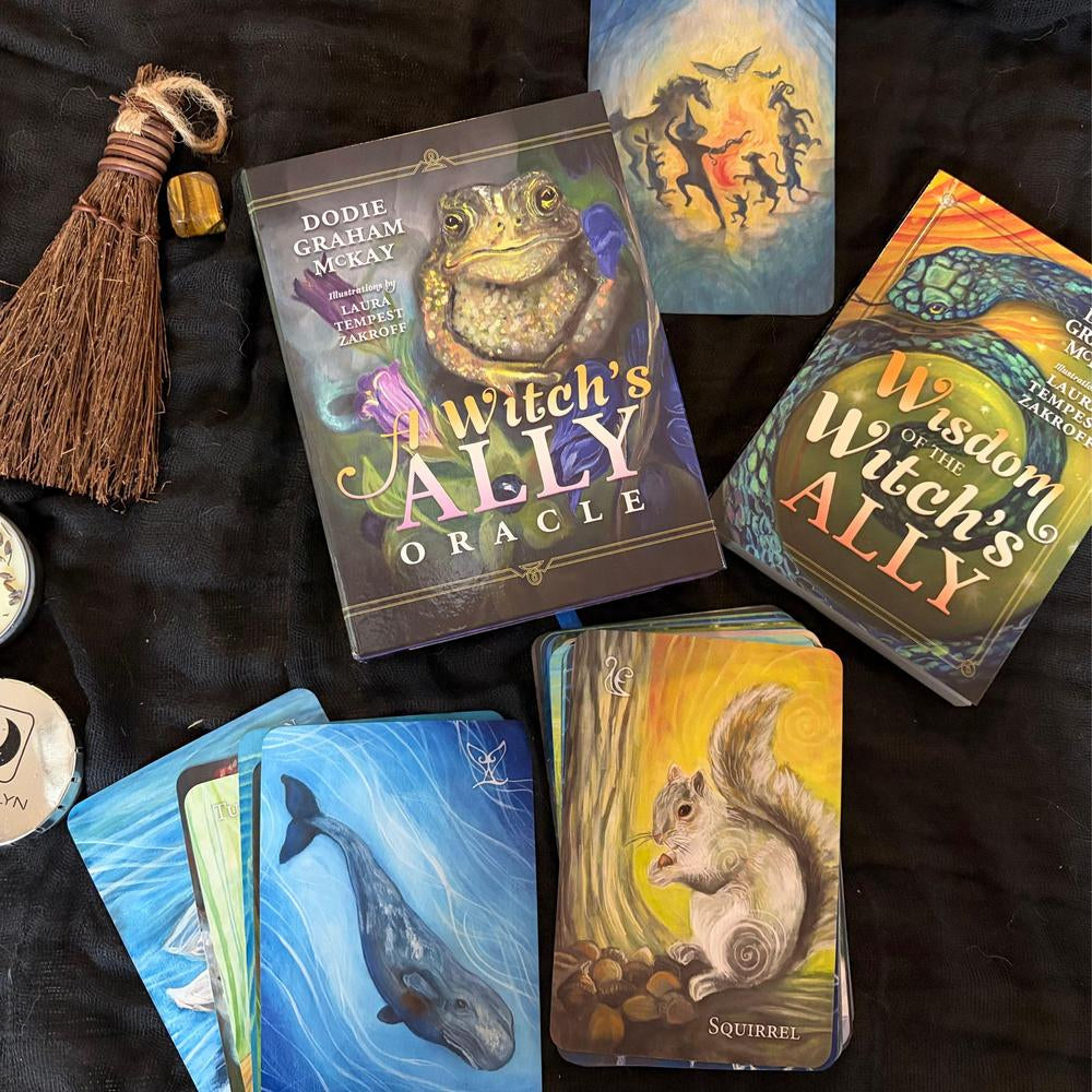 Witch's Ally Oracle cards with a broomstick on a dark fabric background