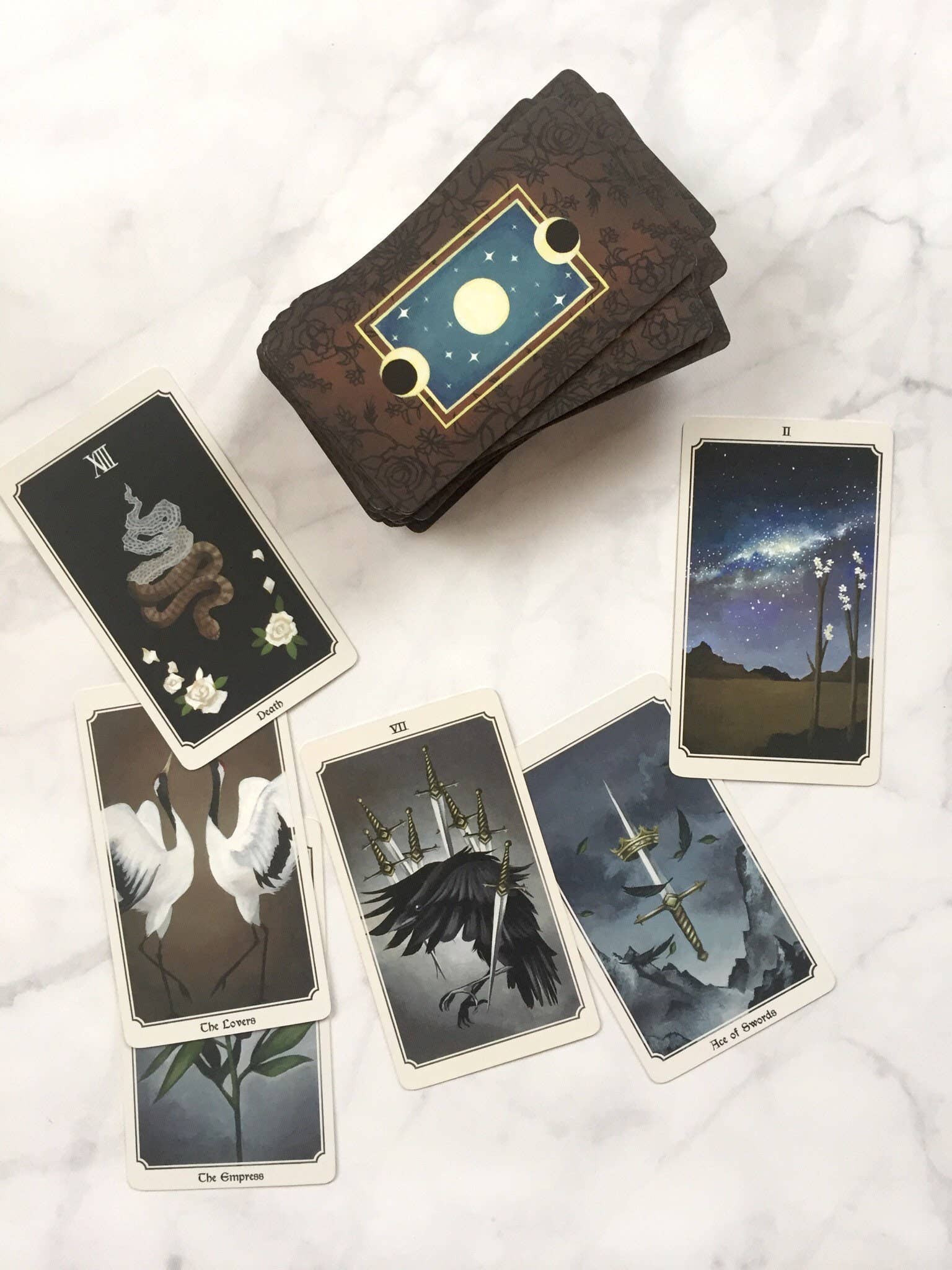 Set of tarot cards with a wooden box on a white marble surface