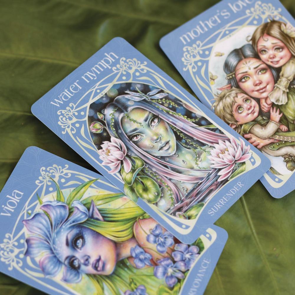 Three tarot cards featuring artistic illustrations of characters with floral elements on a green leaf background.