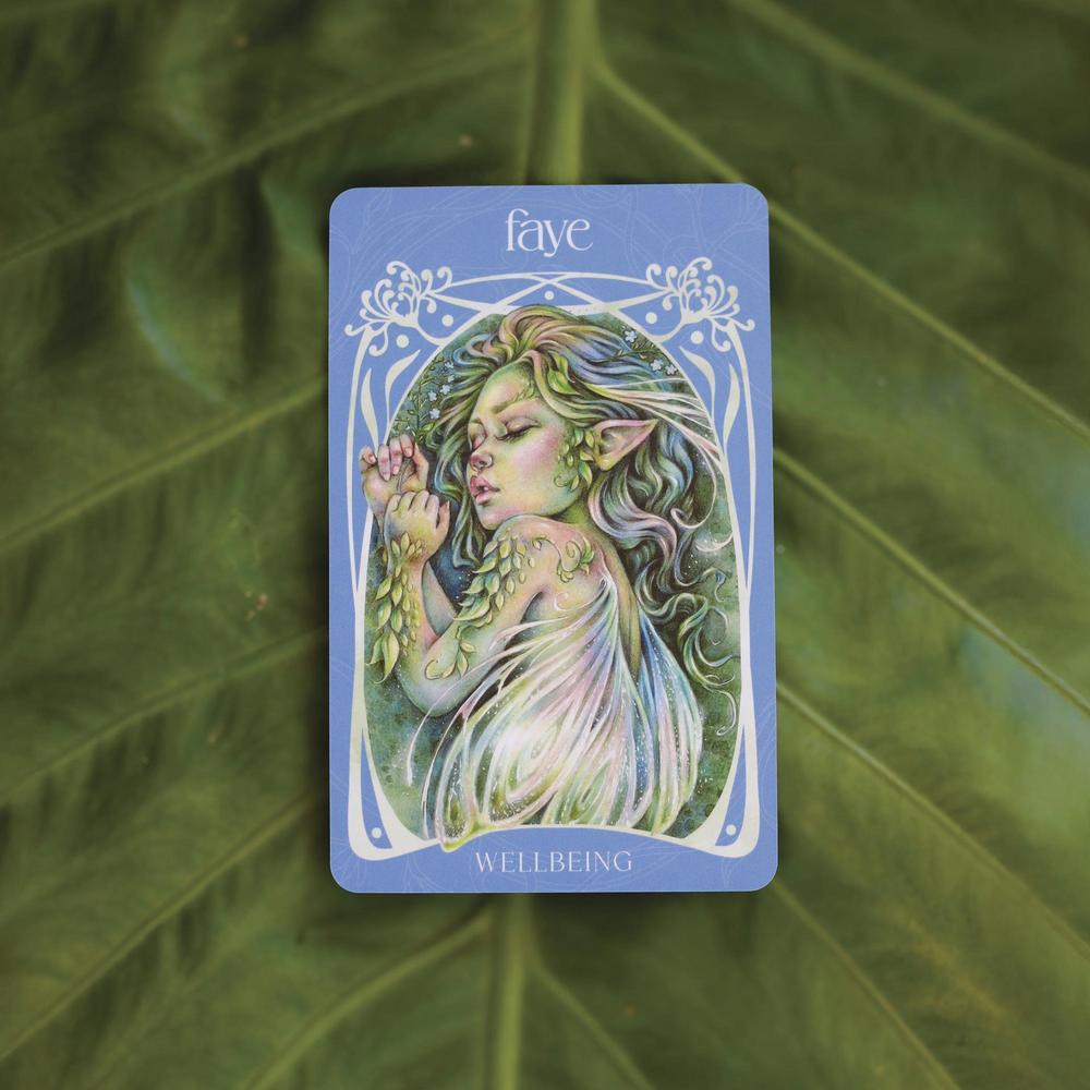 Card featuring a fairy with green hair and leaves, labeled 'Faye' and 'Wellbeing', on a leafy background.