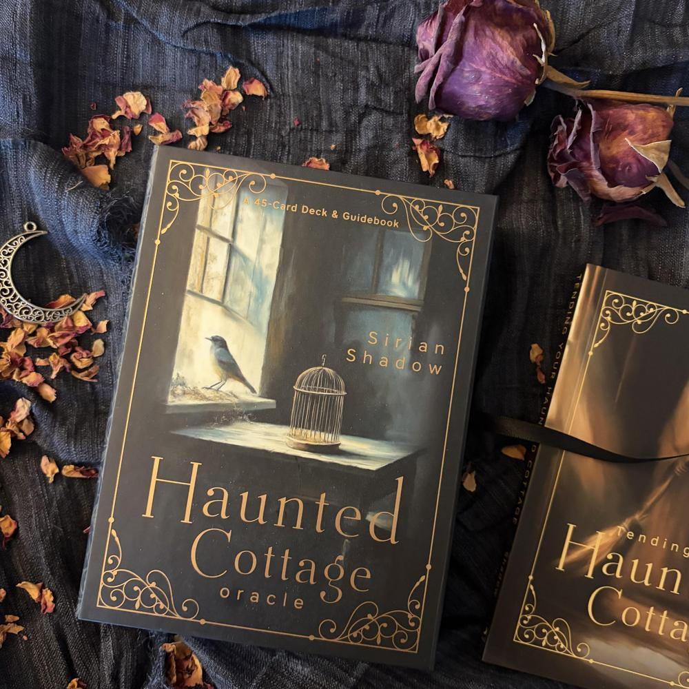 Book titled 'Haunted Cottage Oracle' by Siuan Shadow on a dark fabric background with dried flowers.
