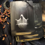 Tarot card with a ghost on a swing, surrounded by dried flowers and a moon pendant.