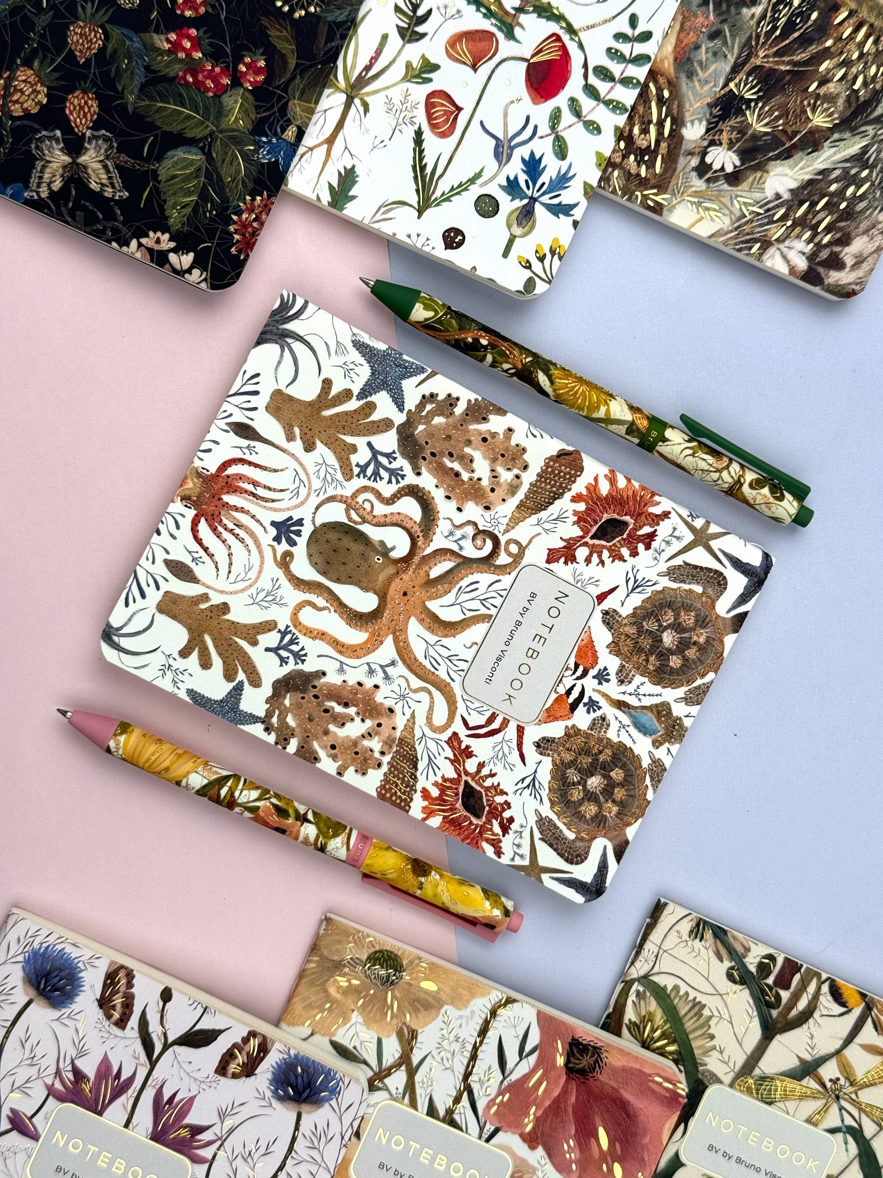 Notebooks with nature-themed designs and matching pencils on a colorful background