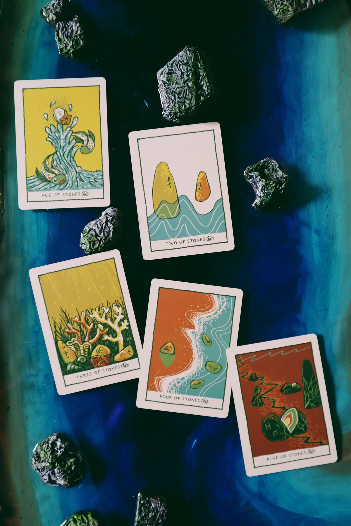 Set of tarot cards with nature-themed illustrations on a blue fabric background with crystals.