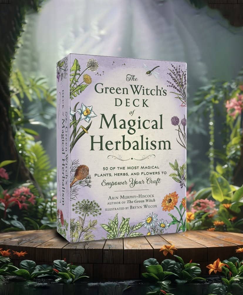 Card deck box titled 'The Green Witch's Deck of Magical Herbalism' on a wooden surface with a forest background.
