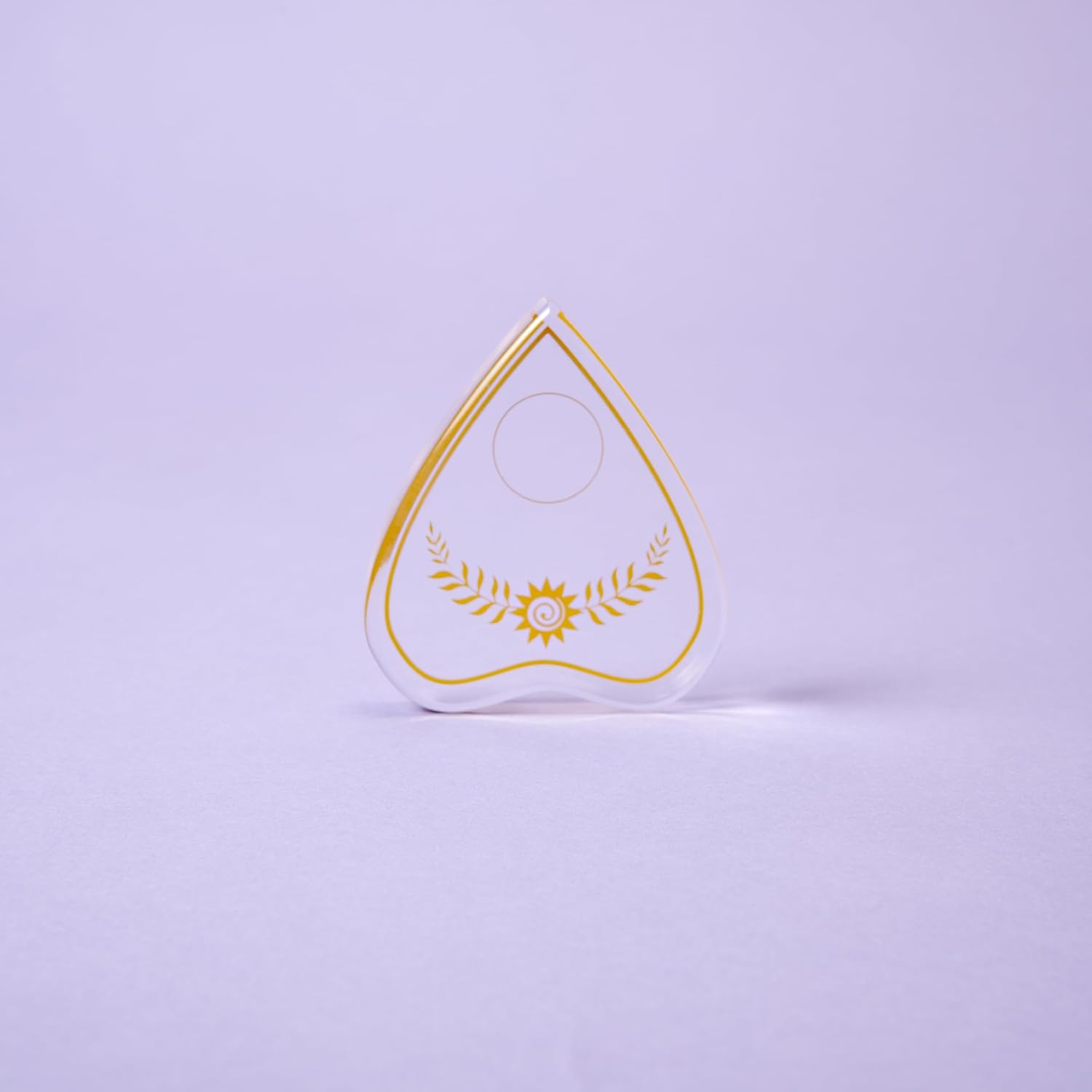 Teardrop-shaped object with gold design on a light purple background