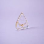 Teardrop-shaped object with gold detailing on a light purple background