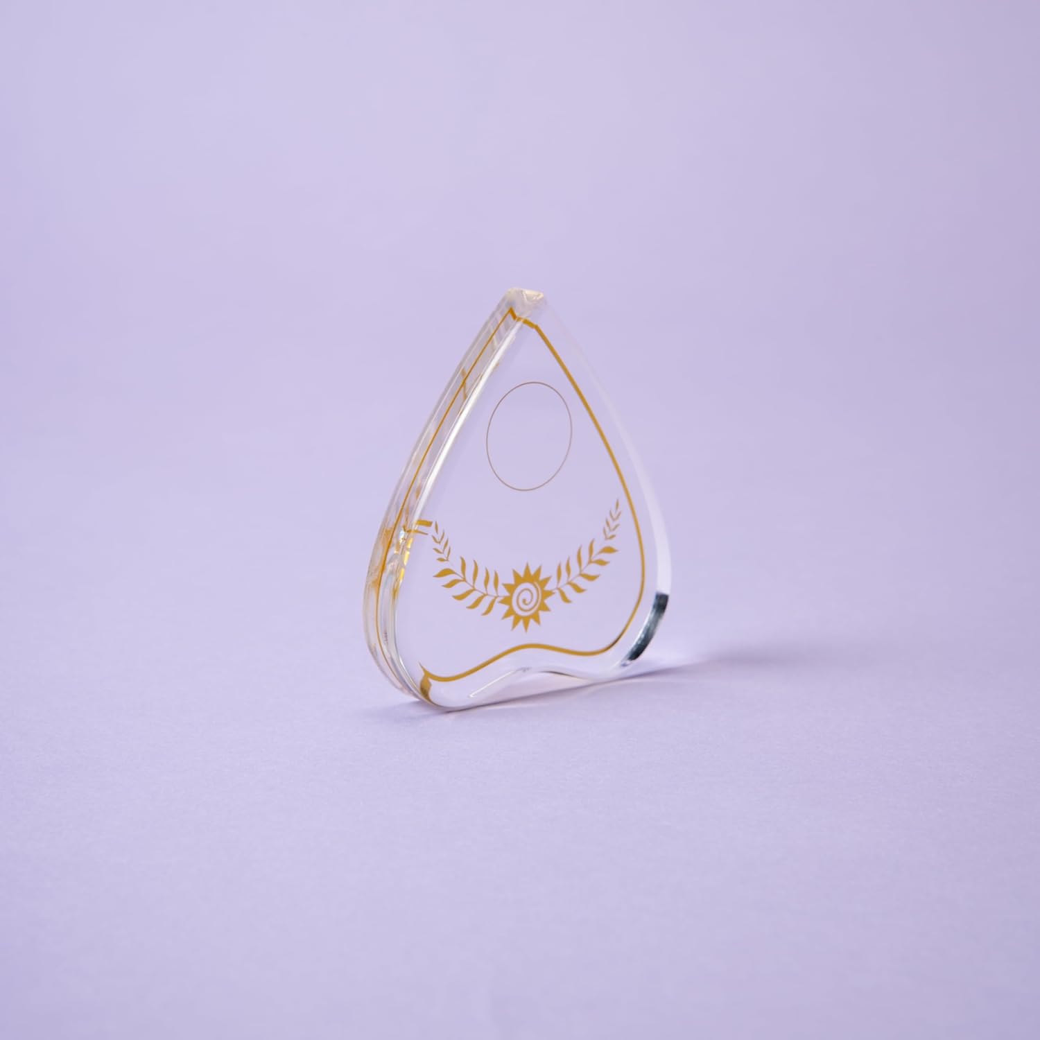 Teardrop-shaped object with gold detailing on a light purple background